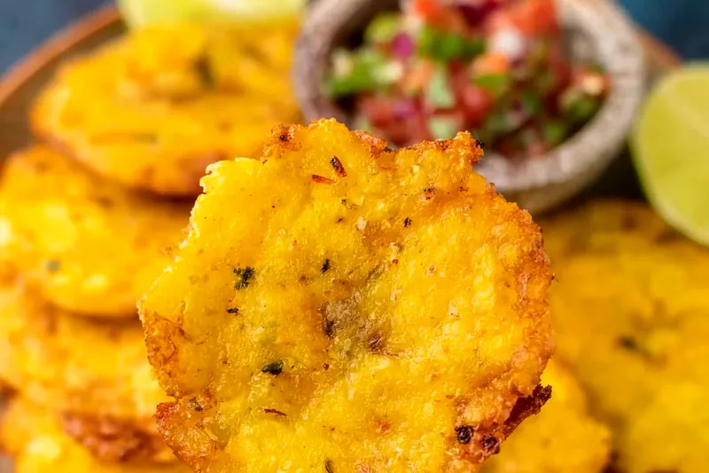 Plantain rounds in an air fryer basket showing the golden color after the first cooking stage, ready to be flattened