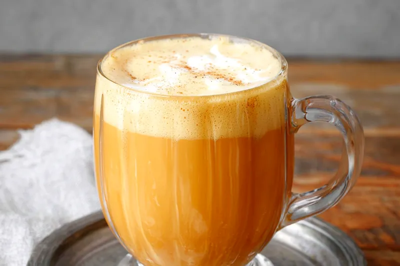 Creamy golden pumpkin milk being gently heated in a saucepan with steam rising, showing the perfect warming technique